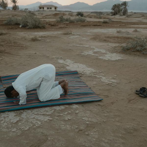 Person meditating outdoors during a serene sunset.